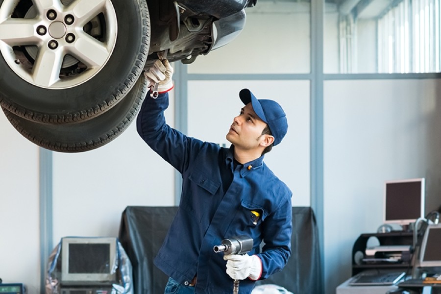GM mechanic working on the underside of a vehicle.