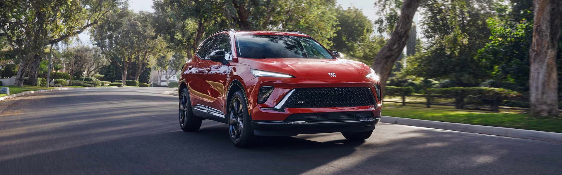 Buick SUV driving on sunny suburban street